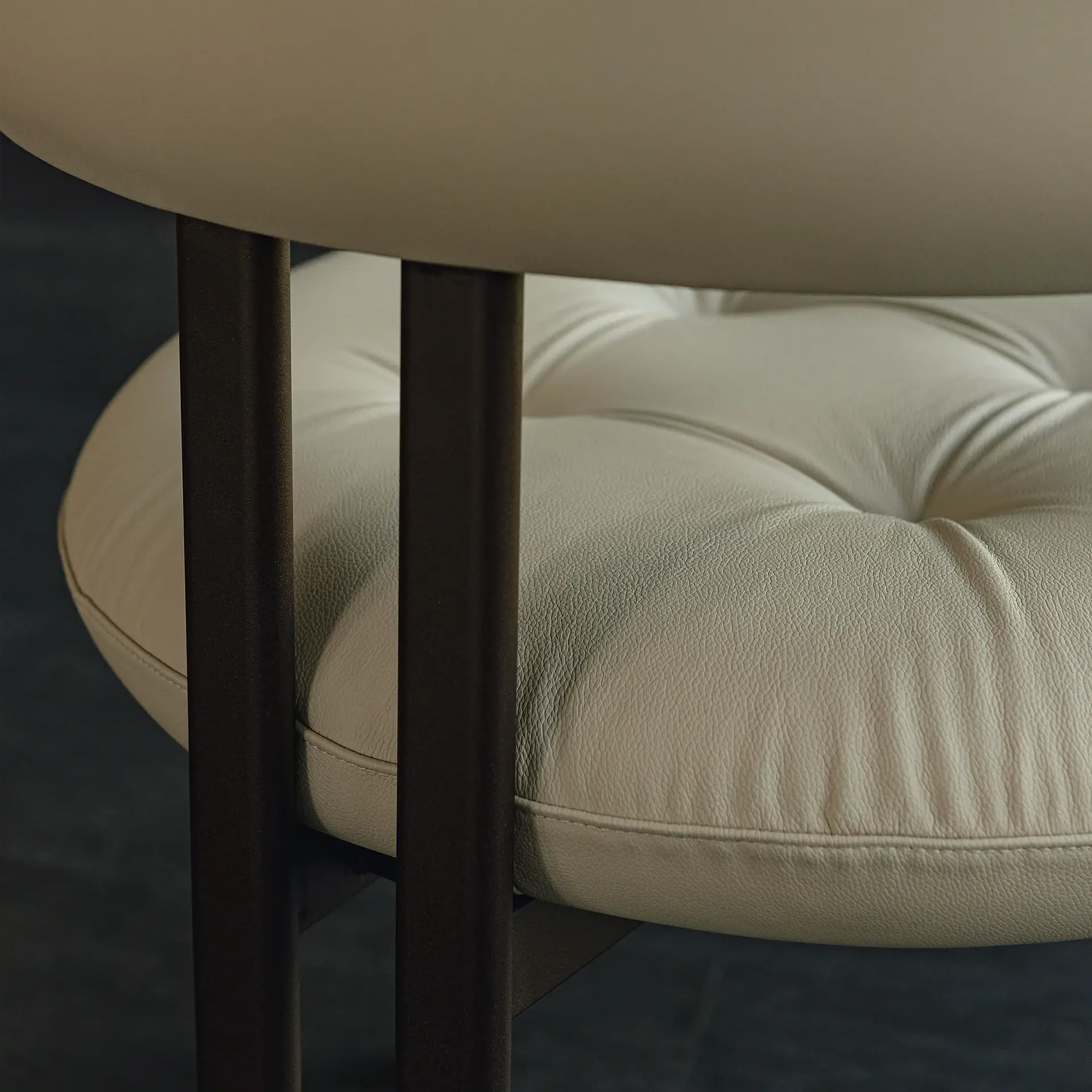 Greta Dining Armchair close-up of cream leather upholstery and dark wooden legs.