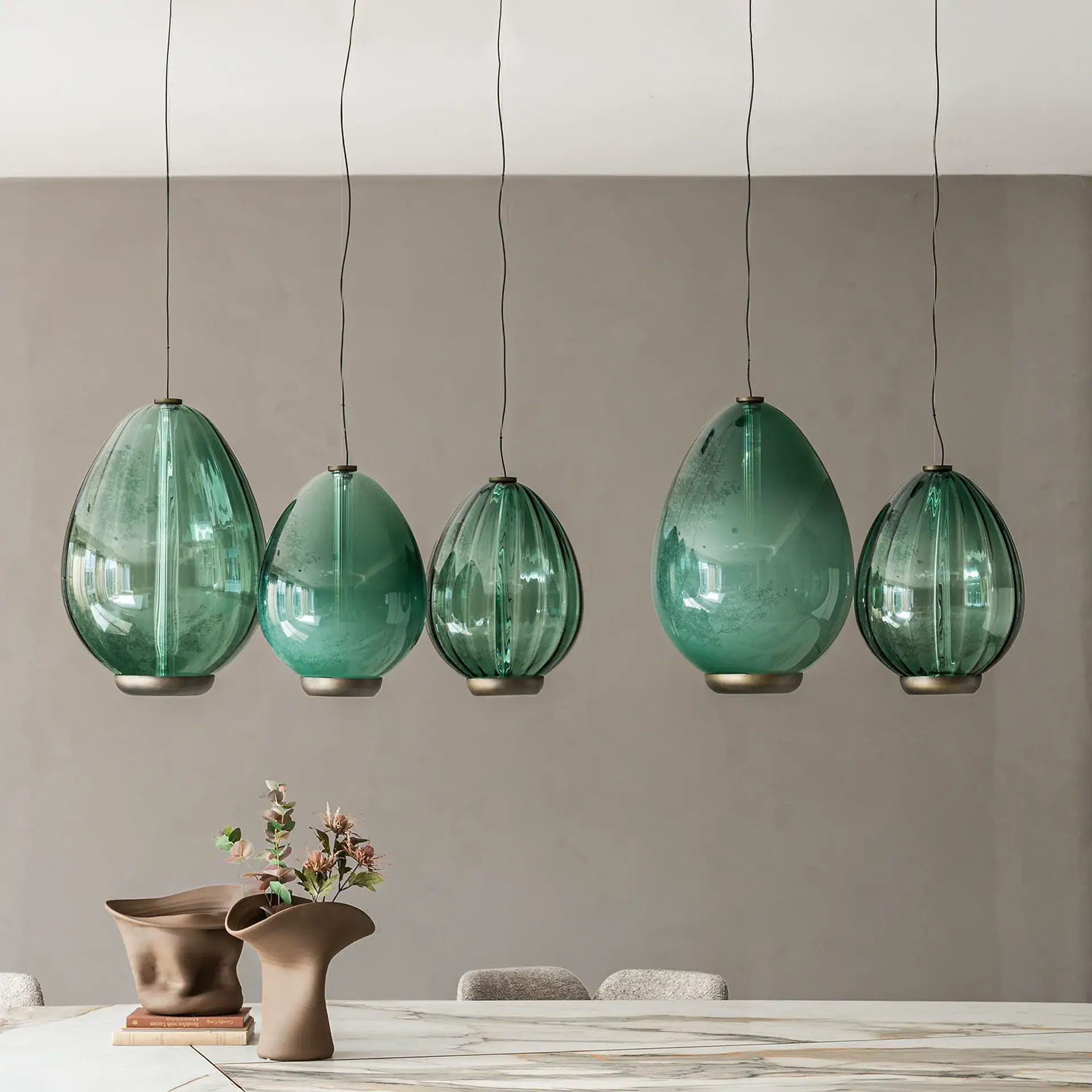 Sklar Furnishings green glass pendant lights hanging over dining table.