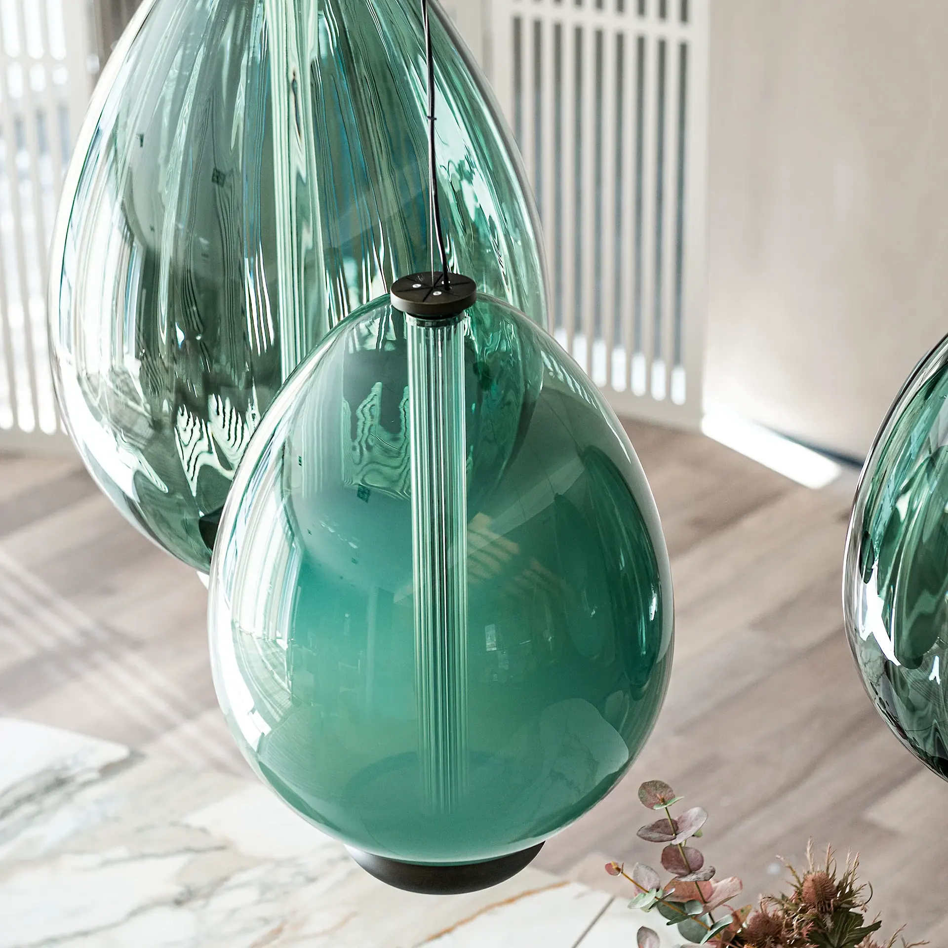 Sklar Furnishings glass pendant light with teal teardrop shade hanging indoors.
