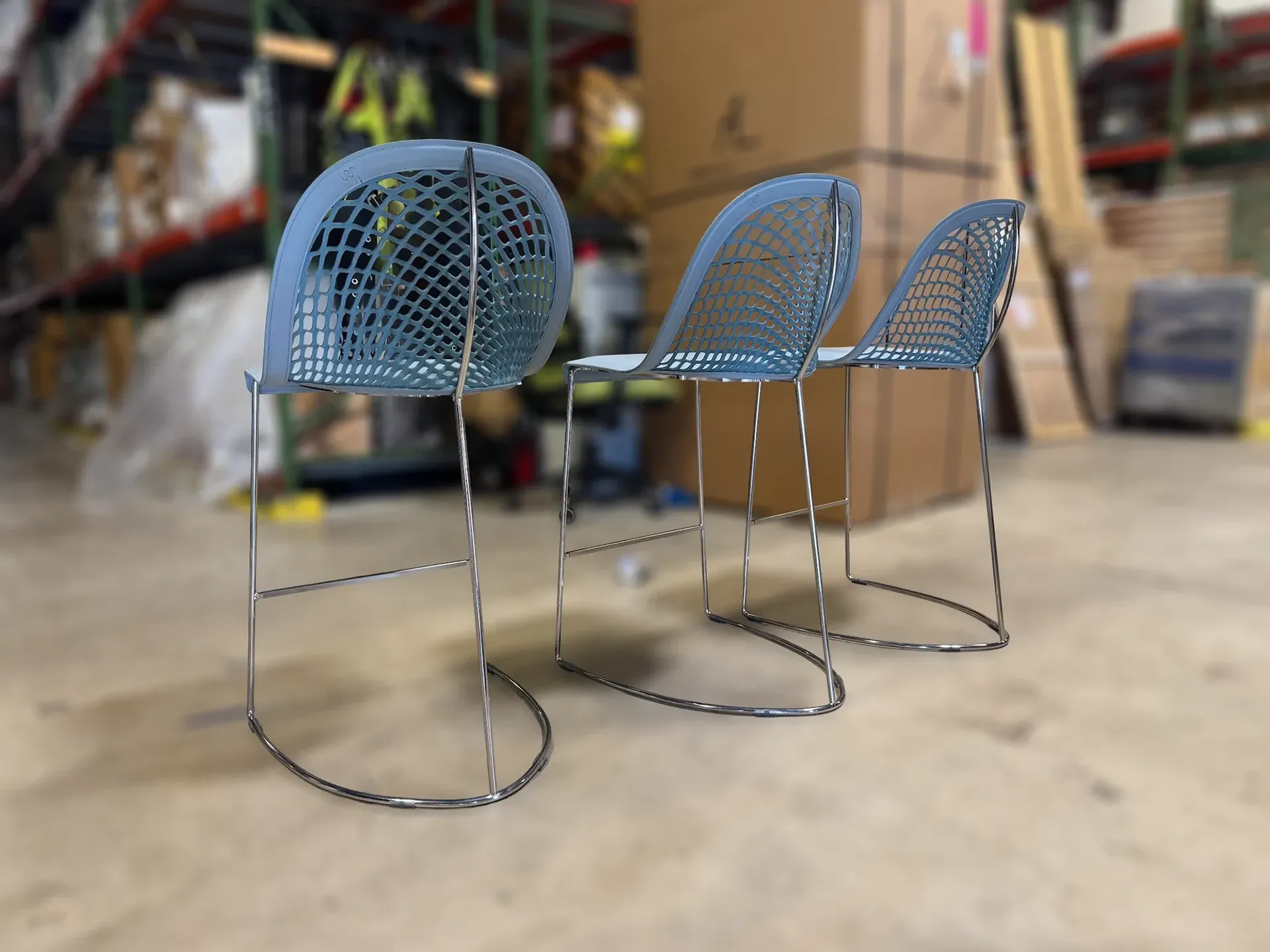Sklar Furnishings counter stool trio in blue with perforated backrest in warehouse.