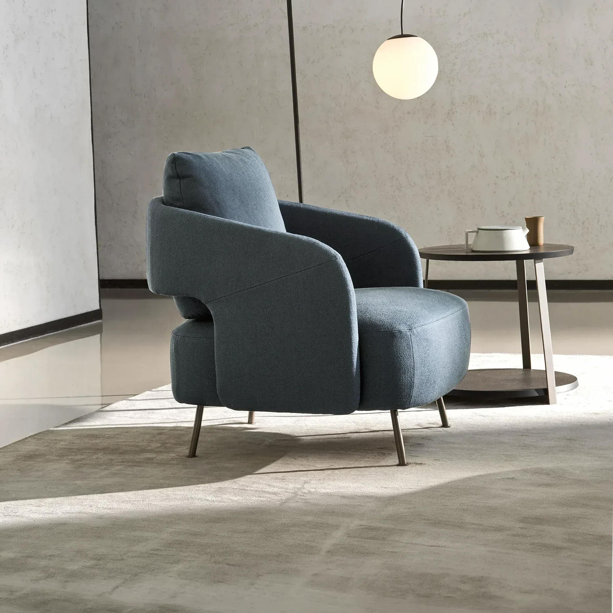 Sklar Upholstered Armchair in blue fabric in a minimalist living space.