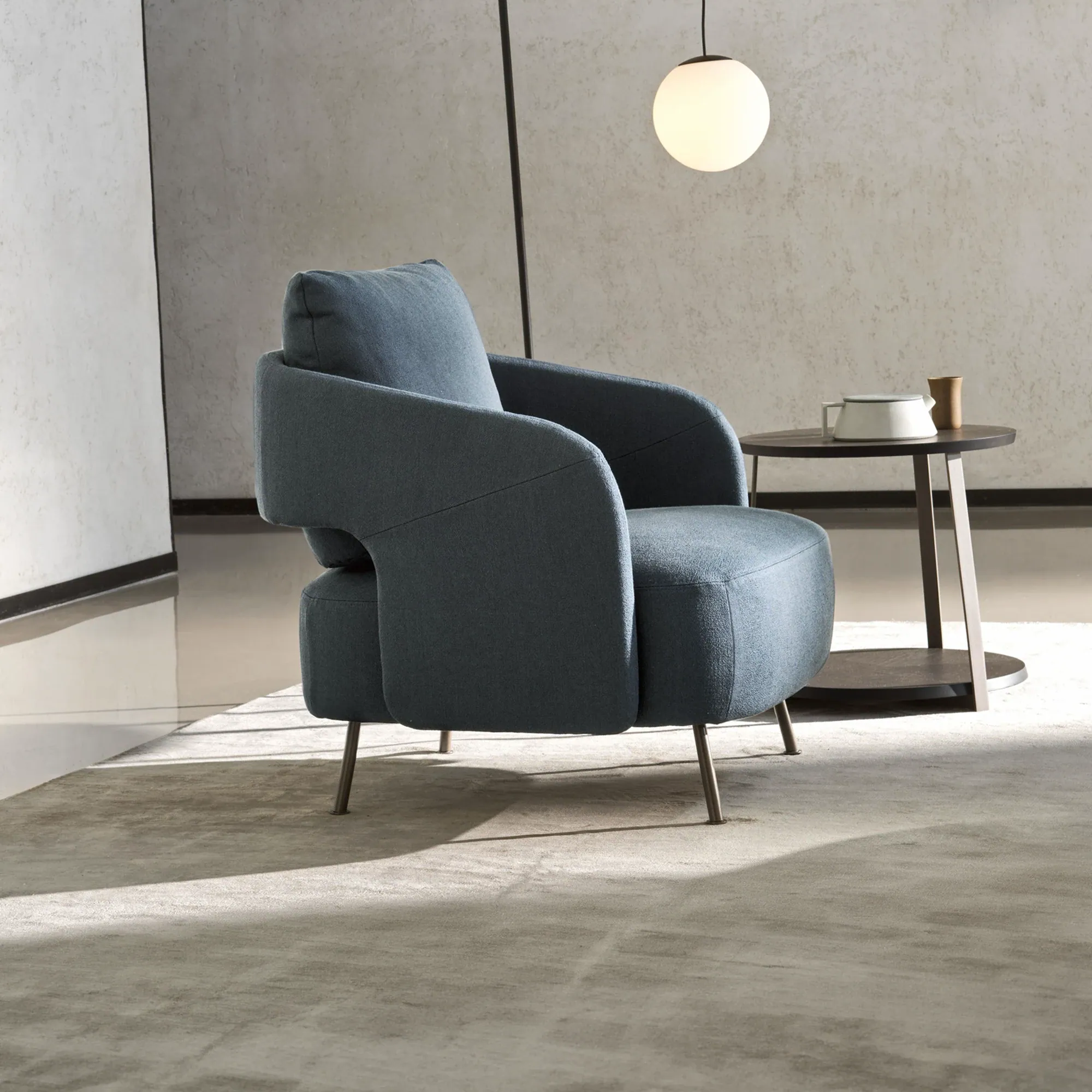 Sklar Furnishings armchair in blue fabric with curved arms and slim legs.