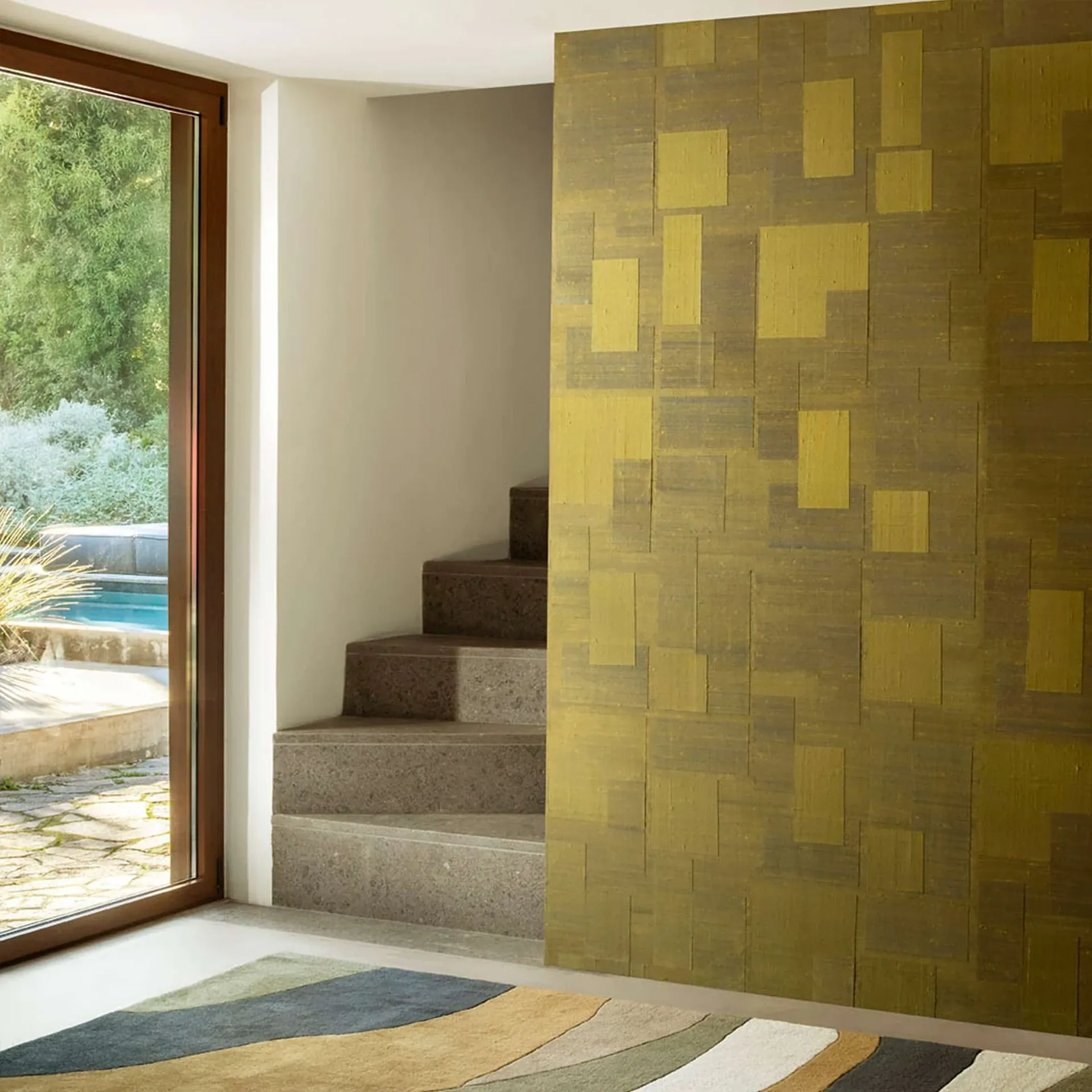 Golden patchwork wall beside stairs and large window.