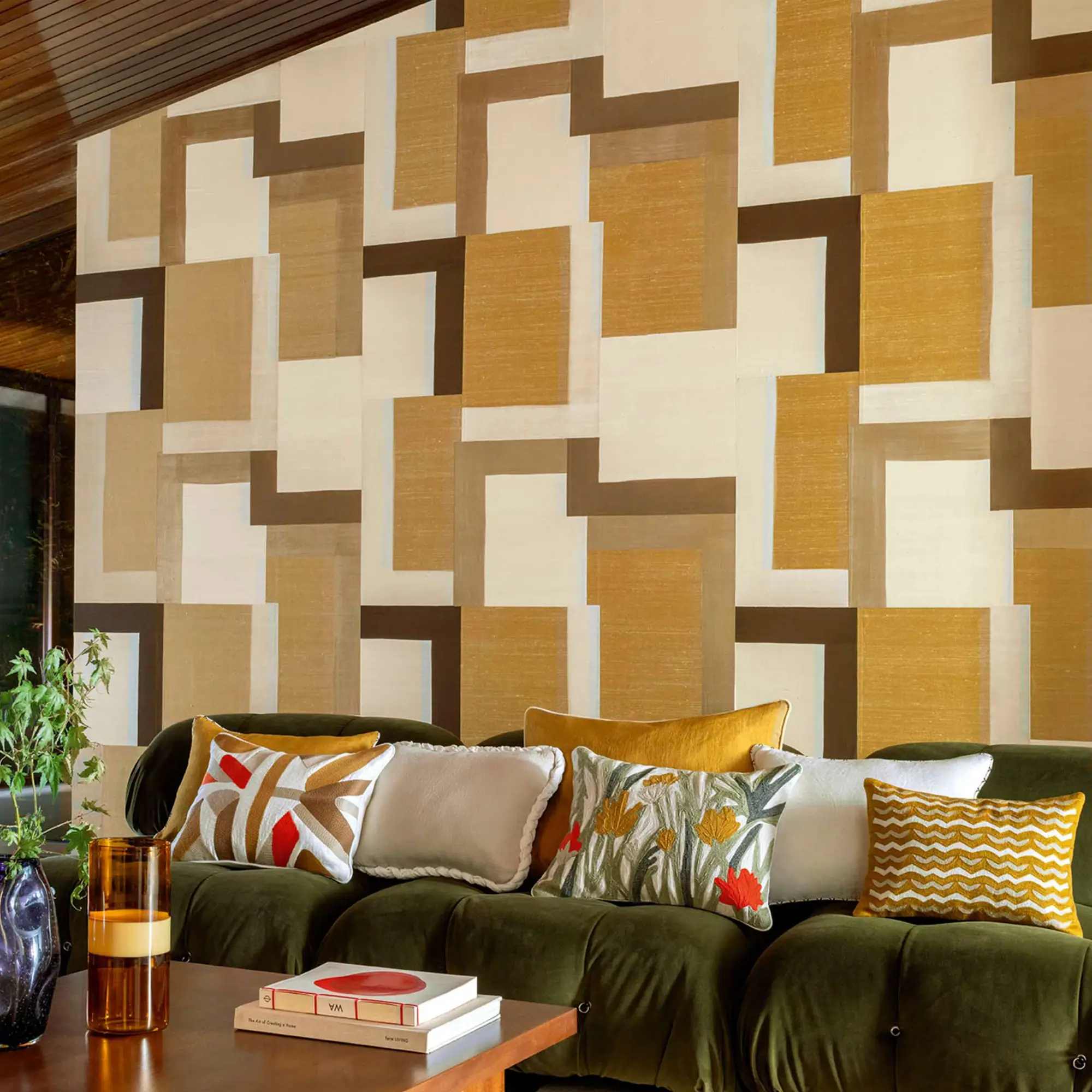 Geometric beige brown wall pattern with green sofa and decorative cushions.