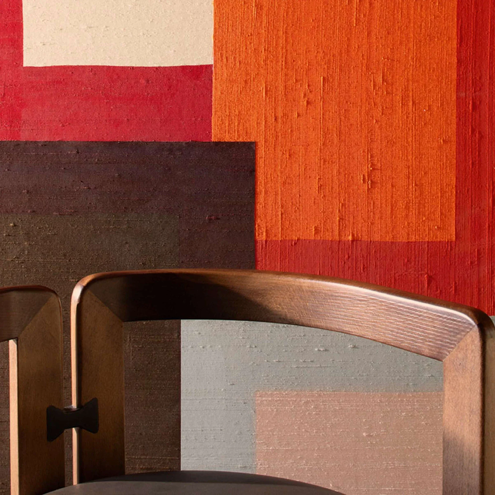 Geometric color blocks on wall with wooden chair back.