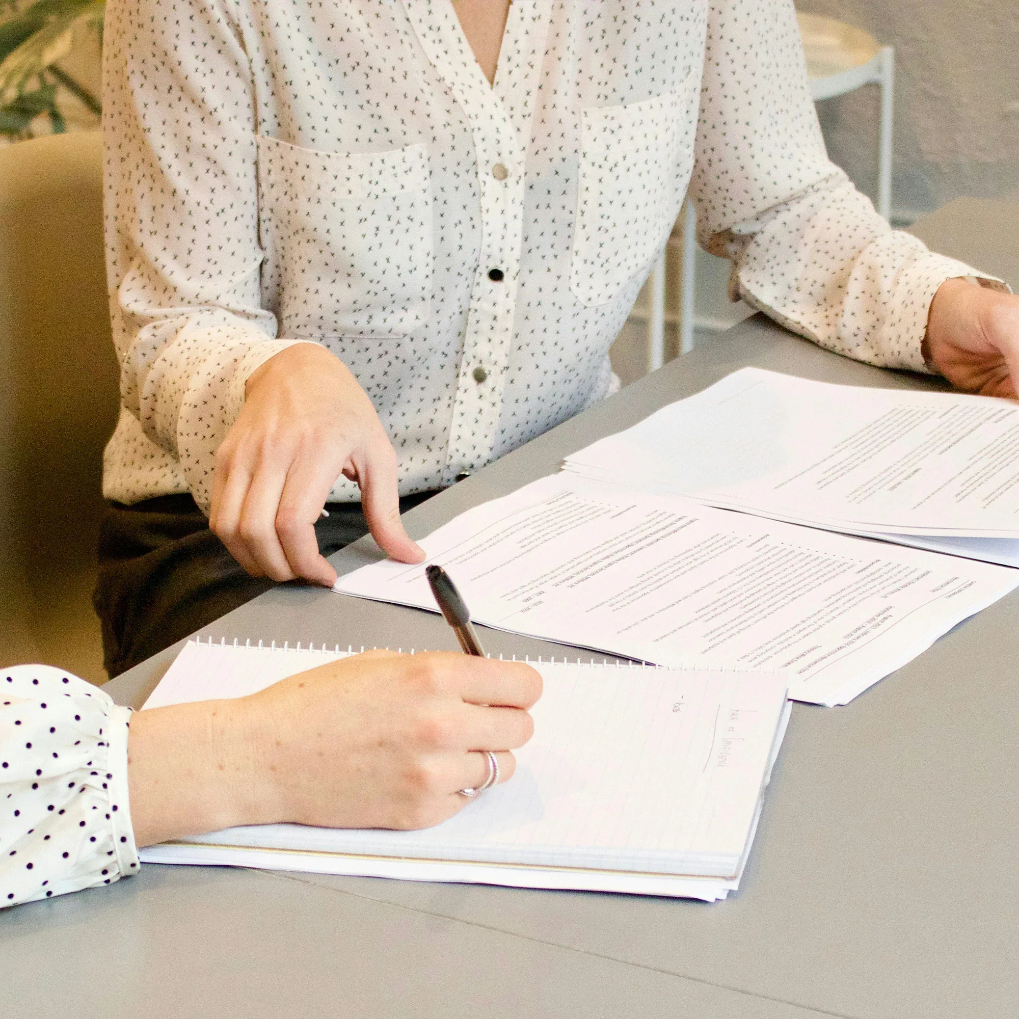 interior-designer-program-administrative-tasks Two women sitting on a sofa, looking at a laptop and fabric swatches.