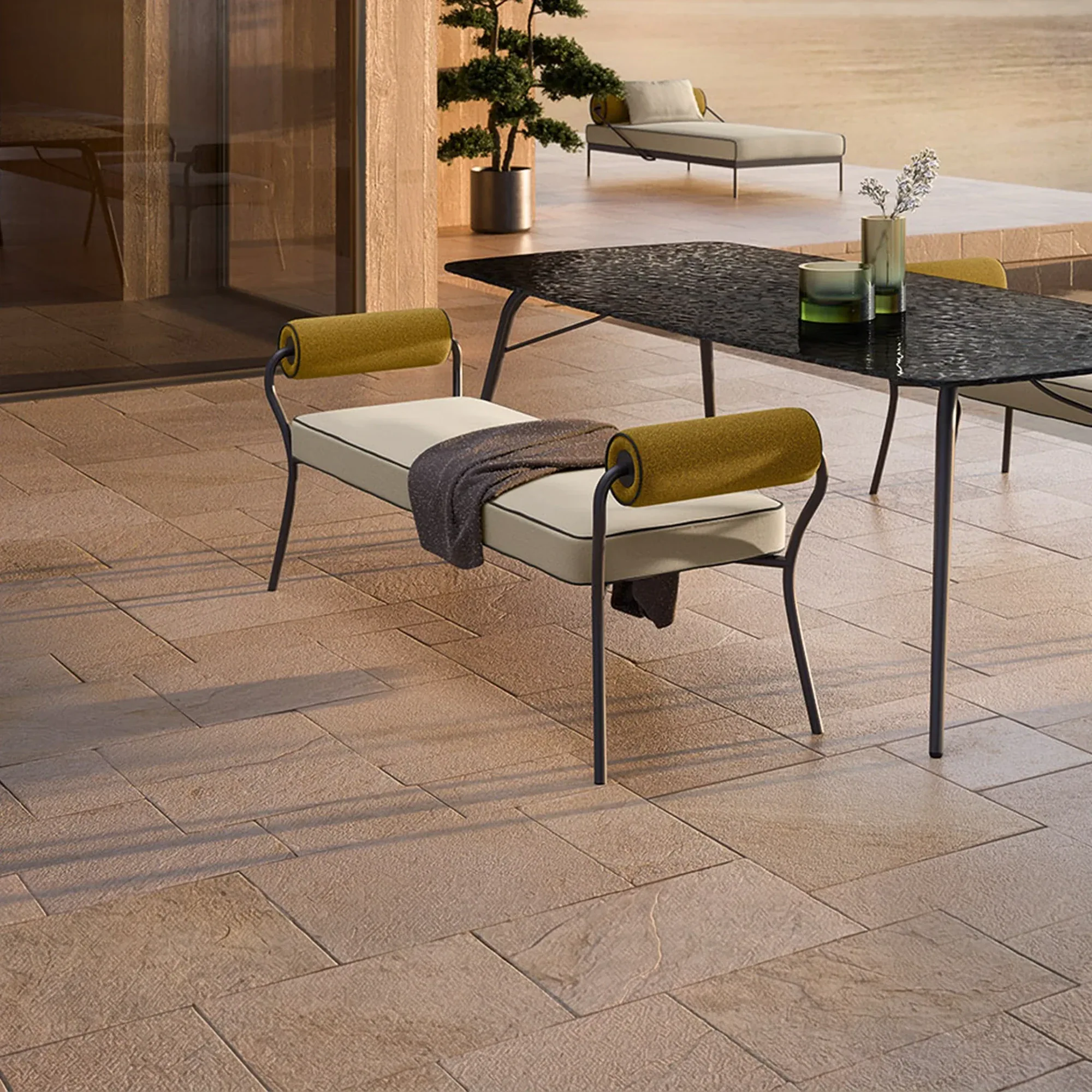 A modern outdoor patio with a bench, dining table, and chaise lounge under warm lighting.