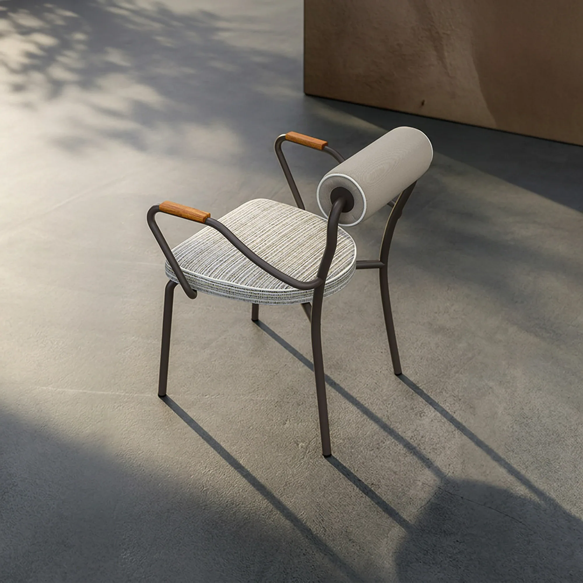 A modern chair with a dark metal frame, striped seat cushion, wooden armrest accents, and a cylindrical backrest sits on a concrete floor with dappled shadows.