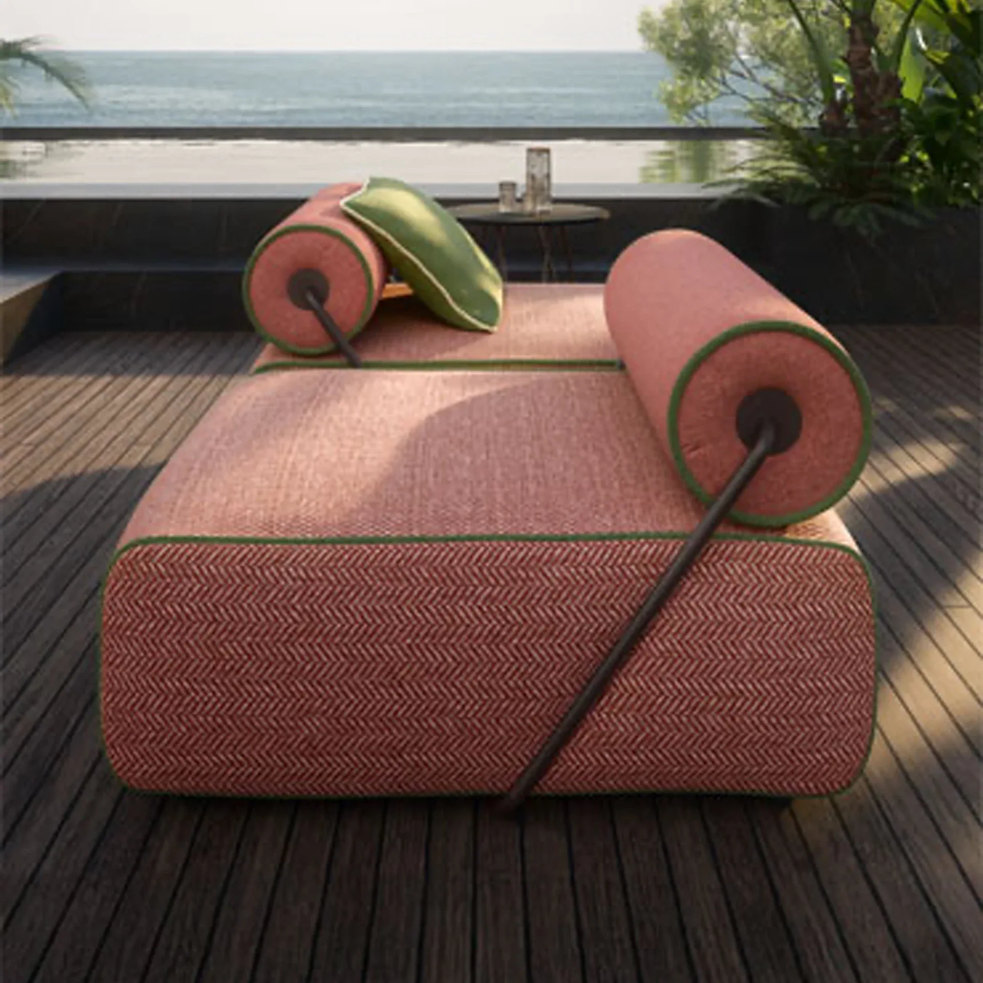 An outdoor daybed with reddish-brown herringbone fabric and green piping, featuring bolsters and a green pillow, set on a wooden deck overlooking an infinity pool and the ocean.