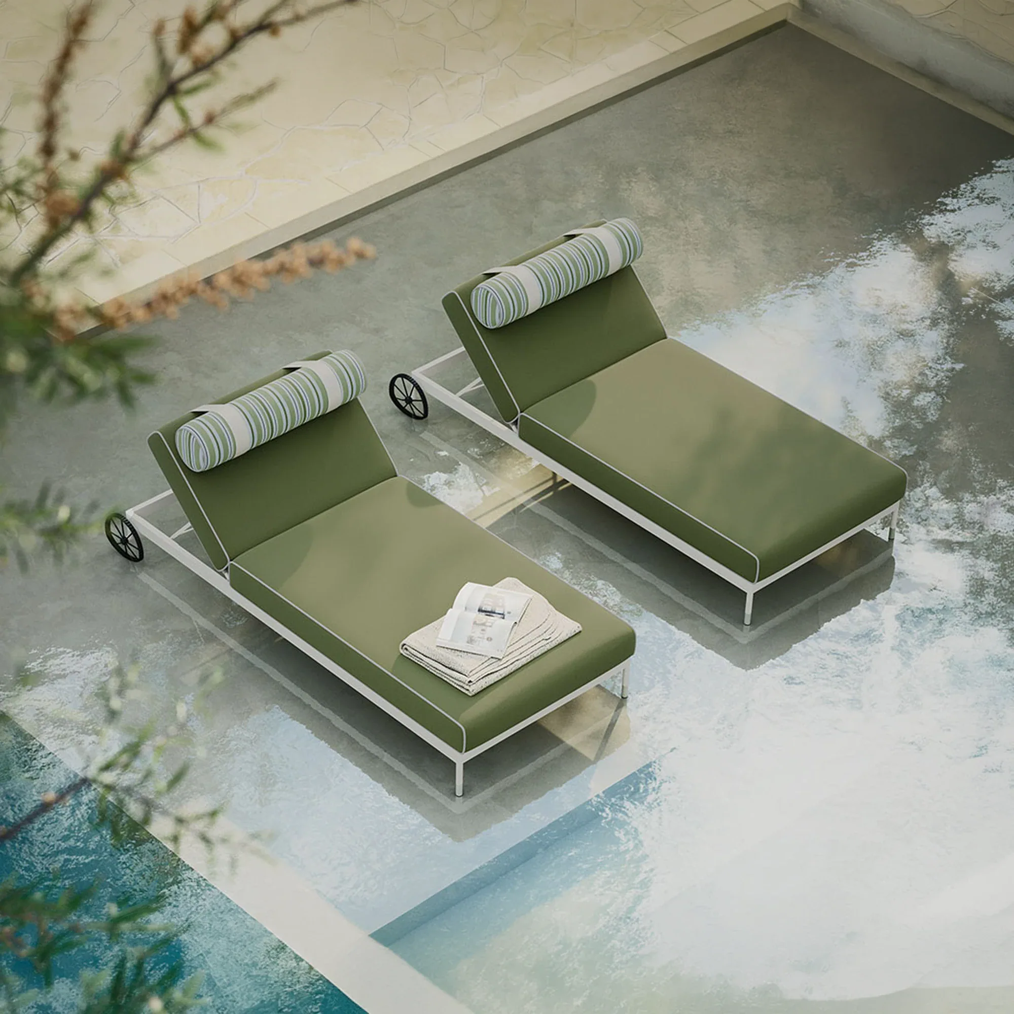 Overhead view of two olive green lounge chairs with white frames and striped pillows on a wet concrete patio next to a blue swimming pool. One chair has a towel and magazine.
