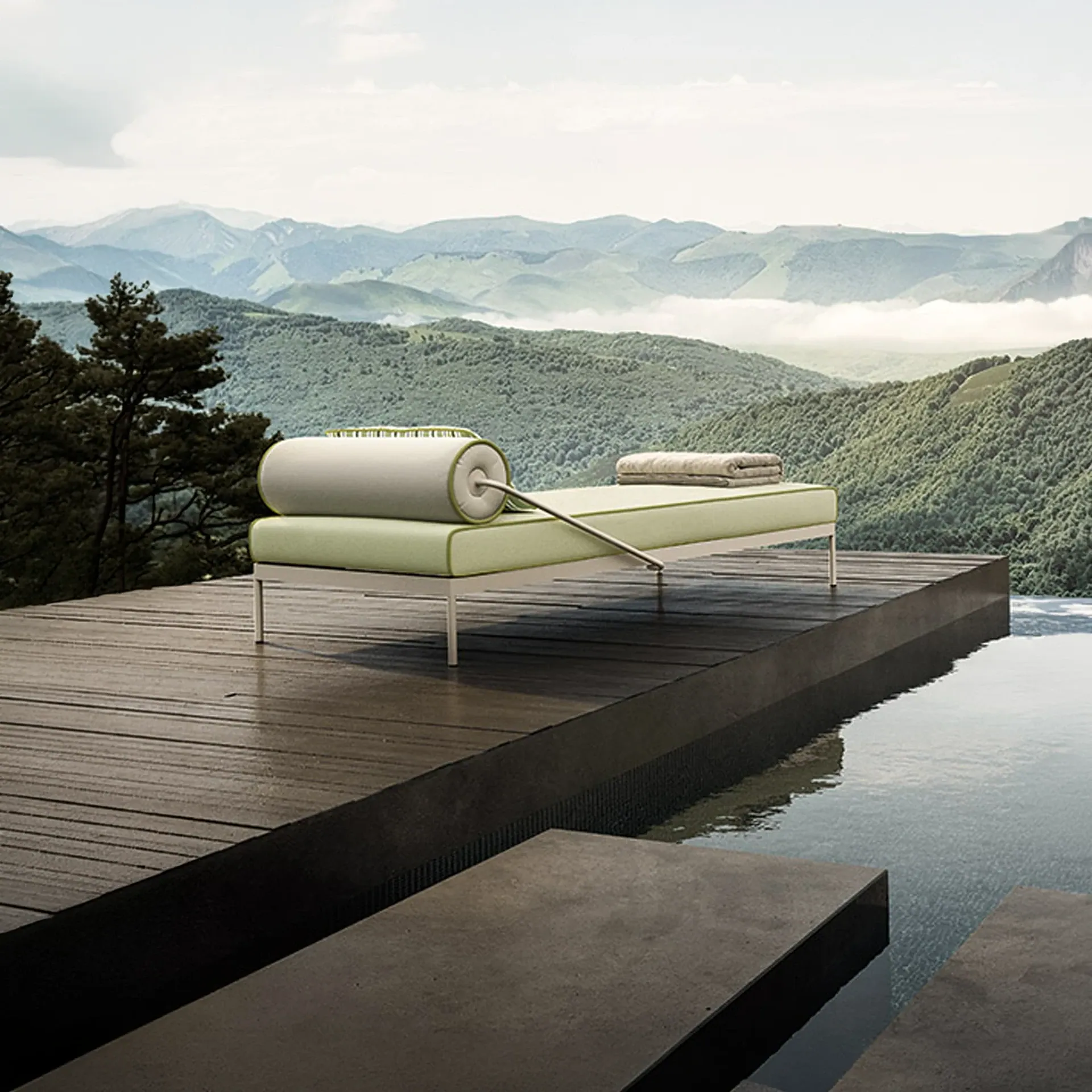 A modern light green chaise lounge with a towel sits on a wooden deck next to an infinity pool, overlooking a vast, misty mountain range.