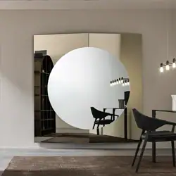 Sklar Furnishings round mirror with black chair and modern decor.