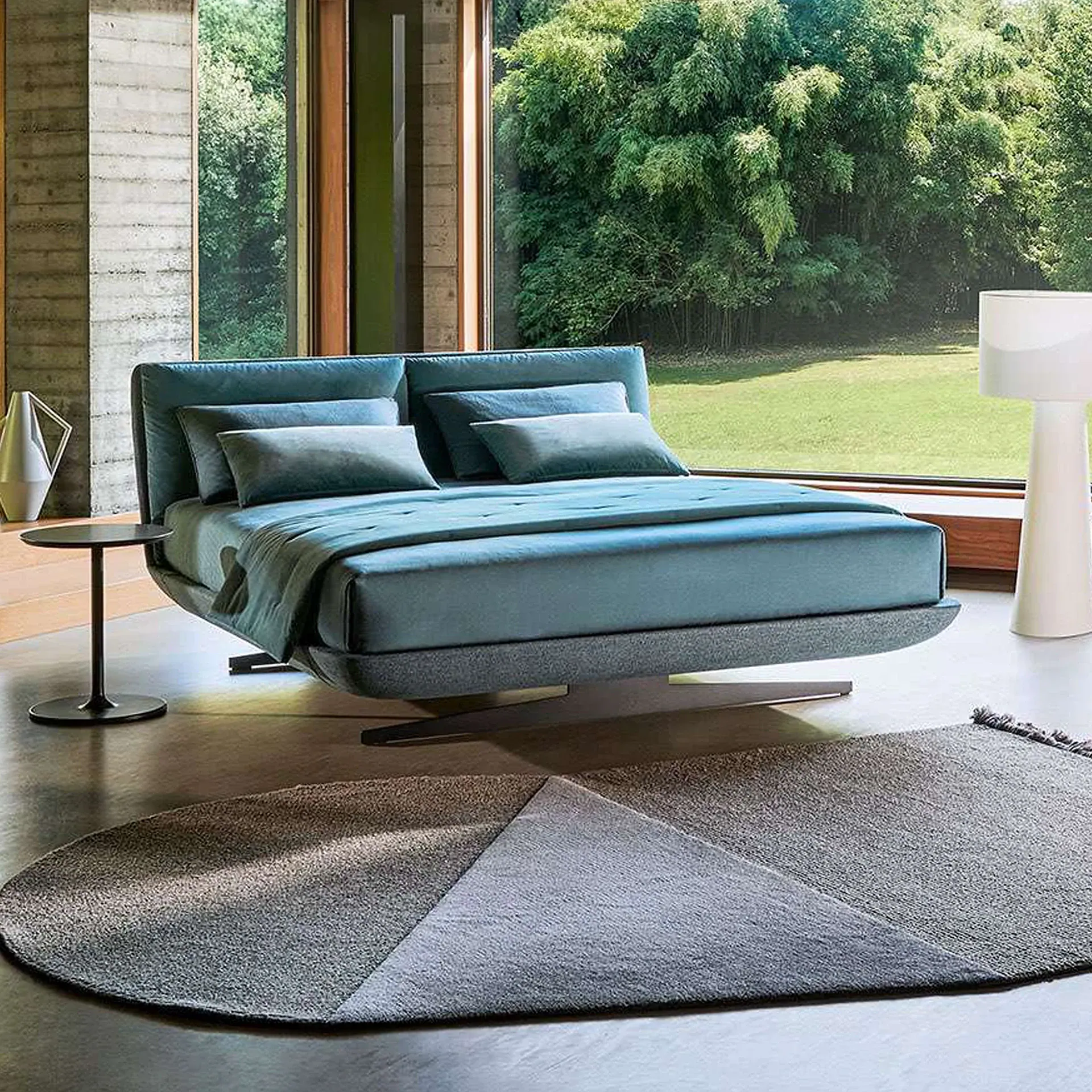 Sklar Furnishings bed in a modern bedroom with blue upholstery and large window view.