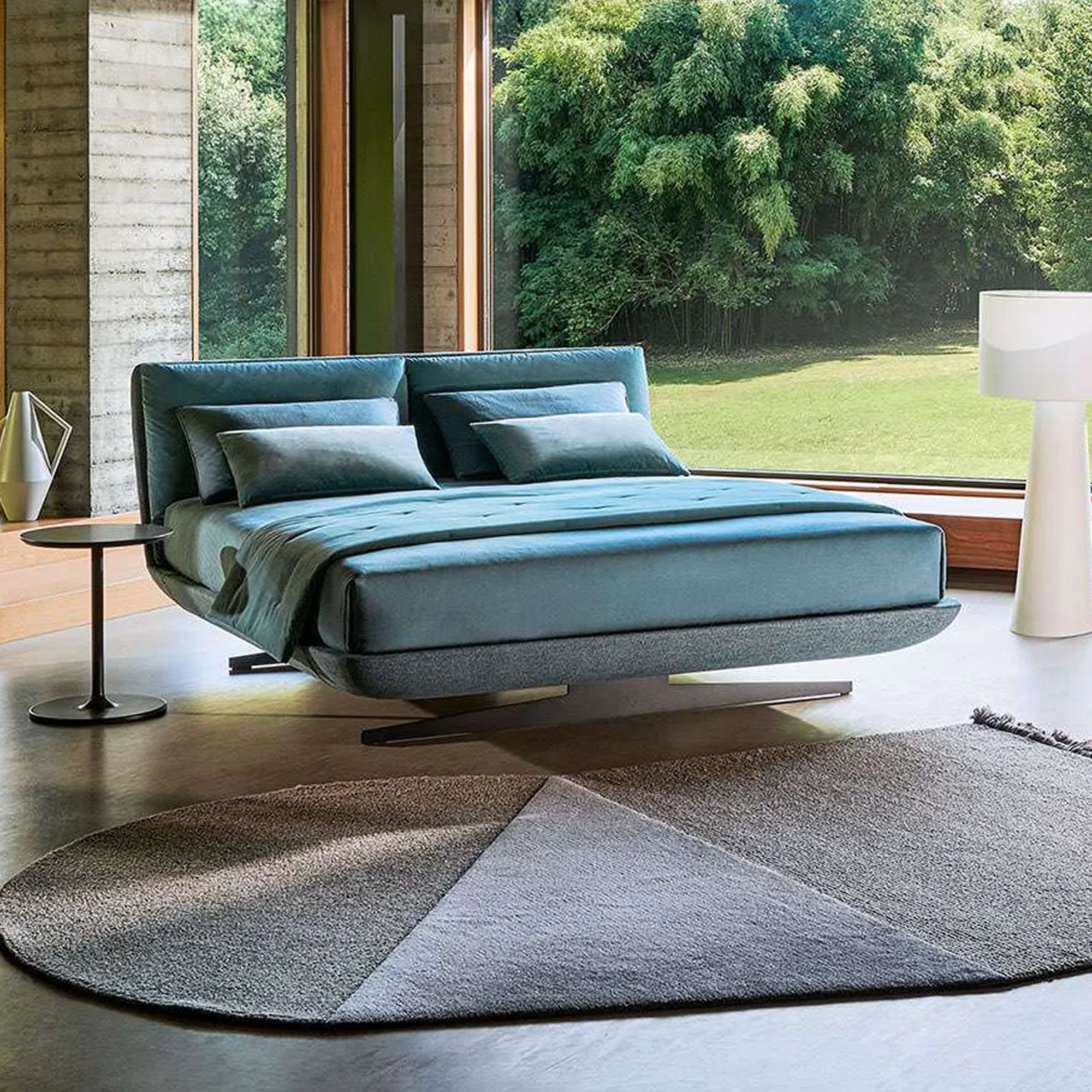 Sklar Furnishings bed in a modern bedroom with blue upholstery and large window view.